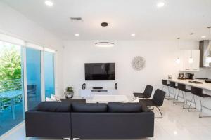 uma sala de estar com um sofá preto e uma cozinha em Across the Ocean few steps to beach contemporary three Bedroom townhouse em Pompano Beach