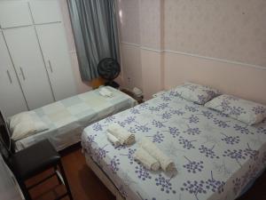 a bedroom with two beds and towels on a bed at Quarto Familiar Aconchegante in Recife