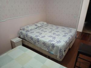 um pequeno quarto com uma cama com um edredão branco em Quarto Familiar Aconchegante no Recife