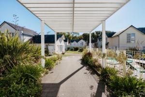 a white pergola over a walkway with houses at Résidence Pierre & Vacances Le Domaine du Bois de la Grée in Pornichet +40 photos