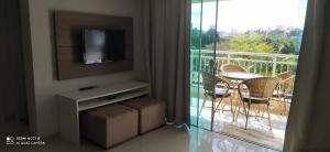 ein Wohnzimmer mit einem TV und einem Balkon mit einem Tisch in der Unterkunft Bombinhas Summer Beach - Apto 303 in Bombinhas + 1 Foto
