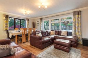 a living room with a leather couch and a table at Hazelglade Cottage - Hot Tub, Games Room, Pet Friendly in Saundersfoot