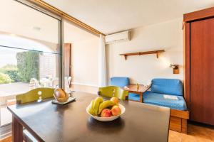 a kitchen with a table with a bowl of fruit on it at Résidence Pierre & Vacances Les Jardins de la Côte d'Azur in Saint-Mandrier-sur-Mer