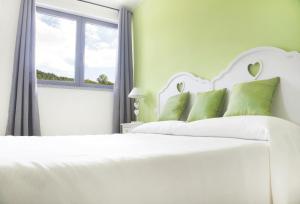un letto bianco con cuscini verdi in una camera da letto di B&B The Divine a Verbania