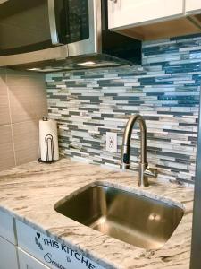 a kitchen counter with a sink and a tile wall at Just Beachy -Ocean View at Symphony Beach Club in Ormond Beach