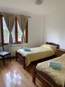 a bedroom with two beds and a chair and a window at La Casa del Arbol - Ushuaia - JUMAX Travel in Ushuaia