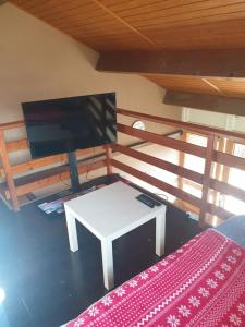 ein Wohnzimmer mit einem TV und einem weißen Tisch in der Unterkunft Duplex de charme avec terrasse in Les Hôpitaux-Neufs