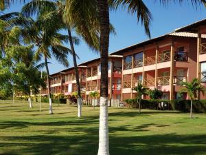 um edifício com palmeiras em frente em Apart Resort Vila das Águas Veraneio em Estância