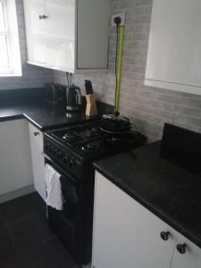 a kitchen with a black stove and white cabinets at Modern property close to Aintree Hospital & Motorways in West Derby