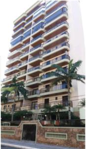 un edificio alto con palmeras delante en Lindo Apartamento no Guarujá - Enseada, en Guarujá