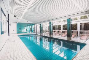 uma grande piscina com cadeiras num edifício em Waldhotel Soodener-Hof em Bad Sooden-Allendorf