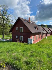 un granero rojo grande en un campo de hierba verde en Apartmány F - chata SVOBODĚNKA, en Dolní Moravice