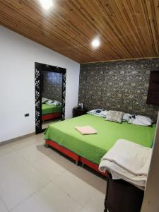 a bedroom with a green bed and a wooden ceiling at Villa del Sol Hotel & Restaurante in Villavieja