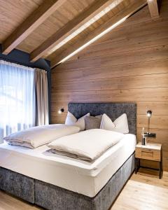 a bedroom with a large bed with a wooden wall at Alpenchalet Tirol in Längenfeld