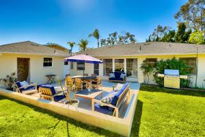 a house with a patio with chairs and an umbrella at DP-343 - Dana Point Parkside Cottage in Capistrano Beach