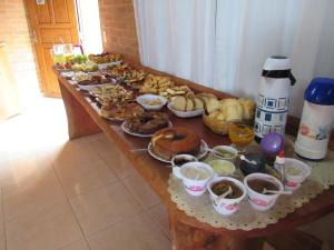 una mesa larga llena de diferentes tipos de alimentos en CHALÉ NATIVO R Júlio Miranda nº 06, en Conceição da Ibitipoca