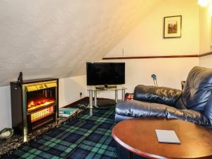 ein Wohnzimmer mit einem Sofa und einem Kamin in der Unterkunft Aberfoyle Apartment in Aberfoyle