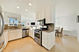 a kitchen with white cabinets and a stove top oven at Newport Pier Townhome in Newport Beach