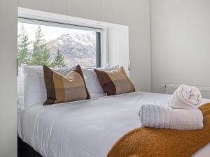 Un dormitorio con una cama blanca con almohadas y una ventana. en The Rata Villa, en Queenstown