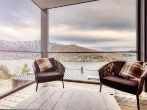 2 sillas en un balcón con vistas al lago en The Rata Villa, en Queenstown
