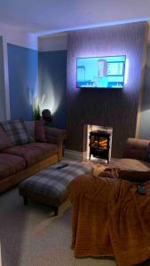 sala de estar con sofá y TV encima de la chimenea en ENAS COVE Homely Getaway, en Derry Londonderry