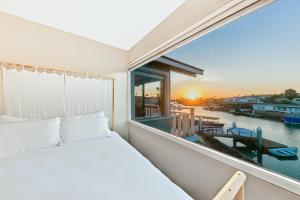 a bedroom with a bed and a window with a view of the water at Newport Bay Front Vacation Home in Newport Beach
