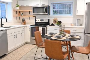 una cocina con armarios blancos y una mesa con sillas. en Modern and warm house en Seattle