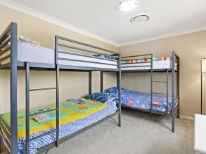 a bedroom with three bunk beds in a house at Ajax Avenue 6 in Nelson Bay