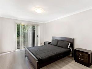 a bedroom with a black bed and a window at Alida Close 1 Lagoons Estate in Nelson Bay