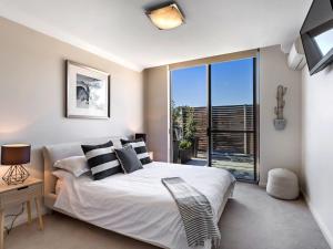 a bedroom with a bed and a large window at Aura Apartments Unit 13 59 Shoal Bay Road in Shoal Bay