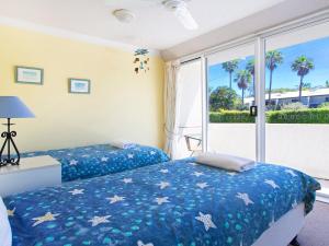 a bedroom with two beds and a window with palm trees at Cote DAzur 6 Douglas Street 6 in Sunshine Beach