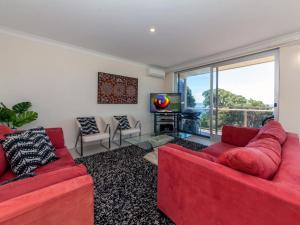a living room with two red couches and a television at Laman Lodge Unit 5 15 Laman Street in Nelson Bay