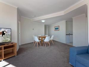 a living room with a table and a blue couch at Barrington, 707/35-45 Shoal Bay Road in Shoal Bay