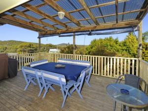 un patio con una mesa azul y sillas en una terraza en Fingal Beach House, en Fingal Bay