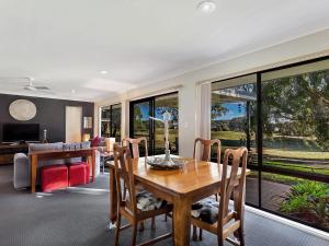 a living room with a wooden table and chairs at Horizons Escape Villa 136 in Salamander Bay