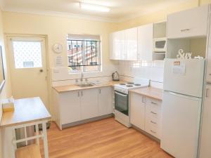 a kitchen with white cabinets and a white refrigerator at Sand and Sea 7 in Sawtell