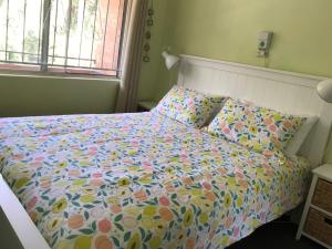 a bedroom with a bed with a floral comforter at Sand and Sea 7 in Sawtell