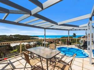 un patio con mesa y sillas y una piscina en Seascape at Diggers Beach Clarence Crescent 11 en Coffs Harbour