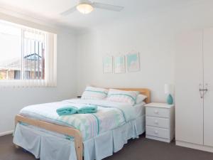 una camera da letto bianca con un letto e una finestra di Tamara Court a Sawtell