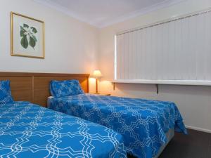een hotelkamer met een blauw bed en een raam bij Horizons Golf Club Villa 135 in Salamander Bay
