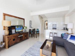 a living room with a couch and a tv at Weyba Quays Townhouse 7 Peza Court 6 in Noosa Heads