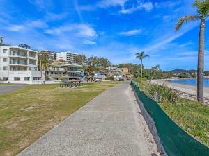 a sidewalk next to a beach with palm trees at Bayview Towers Unit 13 Victoria Parade 15 in Nelson Bay