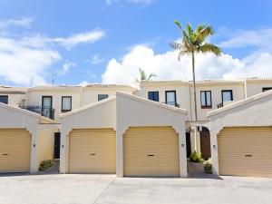 a villa with four garage doors and a palm tree at Weyba Quays Townhouse 7 Peza Court 6 in Noosa Heads