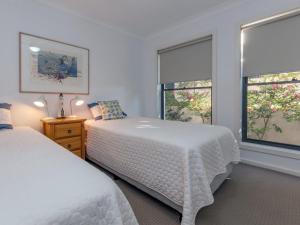 een witte slaapkamer met 2 bedden en 2 ramen bij Beach House 1 20 Pacific Drive in Fingal Bay