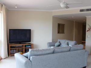een woonkamer met een bank en een flatscreen-tv bij Breakwater 102 Shoal Bay in Shoal Bay