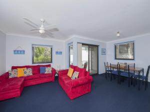 a living room with two red couches and a table at Carindale Unit 21 19 Dowling Street in Nelson Bay