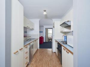 a kitchen with white cabinets and a wooden floor at Carindale Unit 21 19 Dowling Street in Nelson Bay