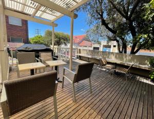 una terraza con sillas, mesas y una pérgola en Cambridge Lodge, en Sídney