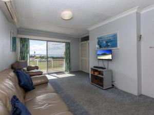 a living room with a couch and a large window at Castaways Unit 1 17 Shoal Bay Road in Shoal Bay