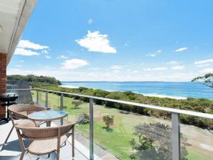 a balcony with a table and chairs and the ocean at Luskin Lodge Unit 15 29 Weatherly Close in Nelson Bay